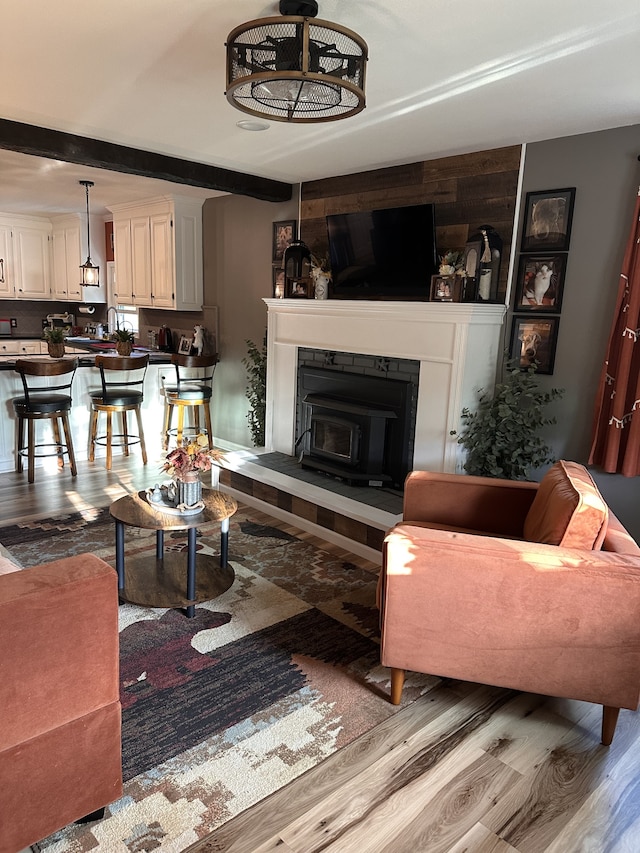 living room with beamed ceiling, sink, and light hardwood / wood-style floors