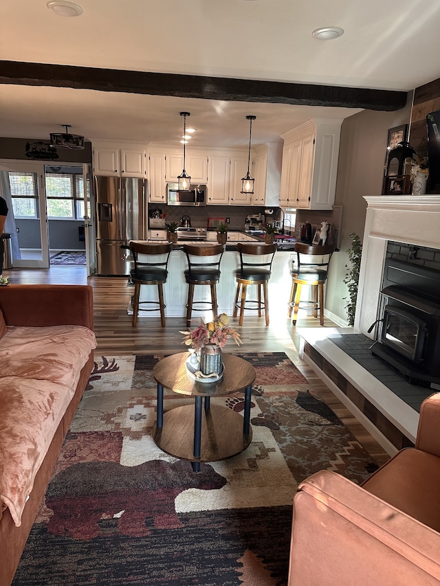 living room with beam ceiling, a wood stove, and dark hardwood / wood-style flooring