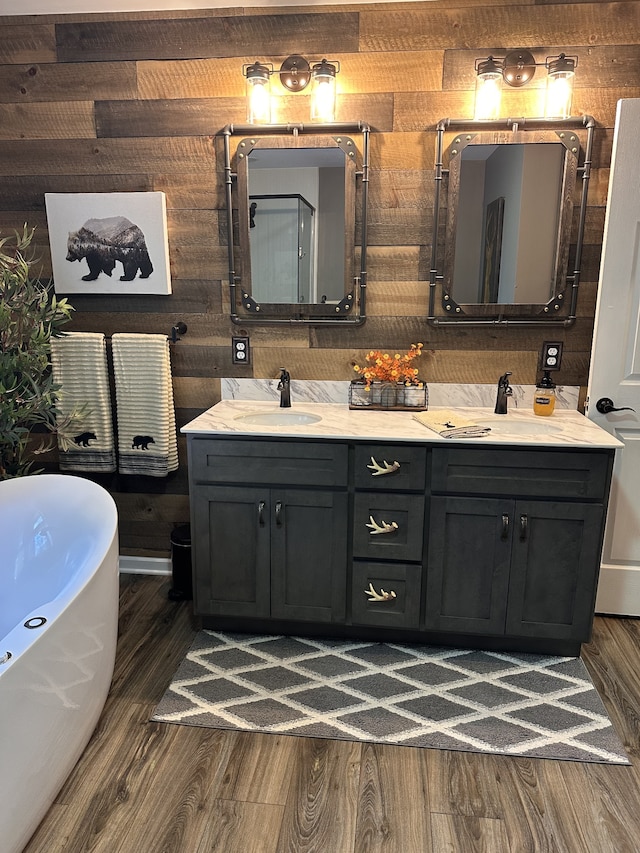 bathroom featuring hardwood / wood-style floors, a tub to relax in, wooden walls, and vanity