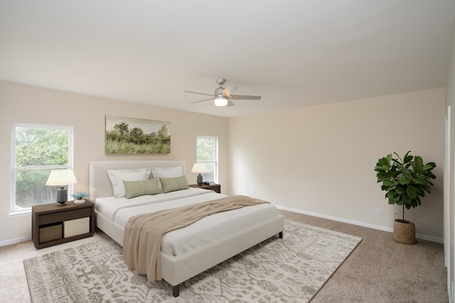 carpeted bedroom featuring multiple windows and ceiling fan