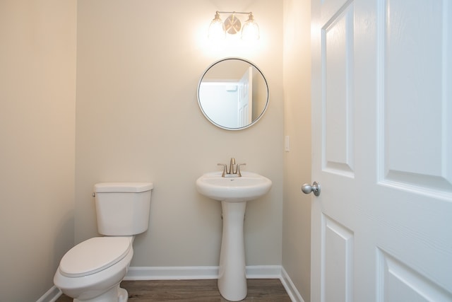 bathroom featuring toilet, sink, and wood-type flooring