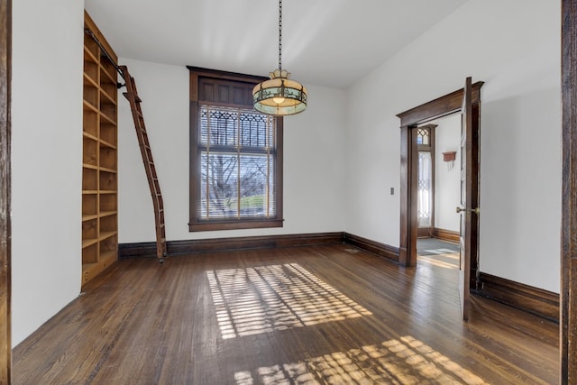 unfurnished dining area featuring a barn door and dark hardwood / wood-style floors