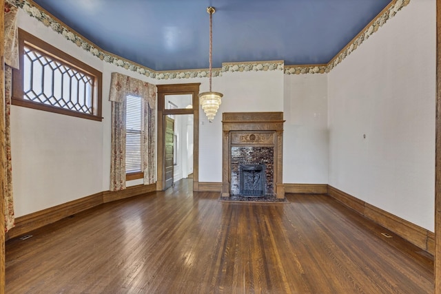 unfurnished living room featuring an inviting chandelier, a fireplace, and dark hardwood / wood-style flooring