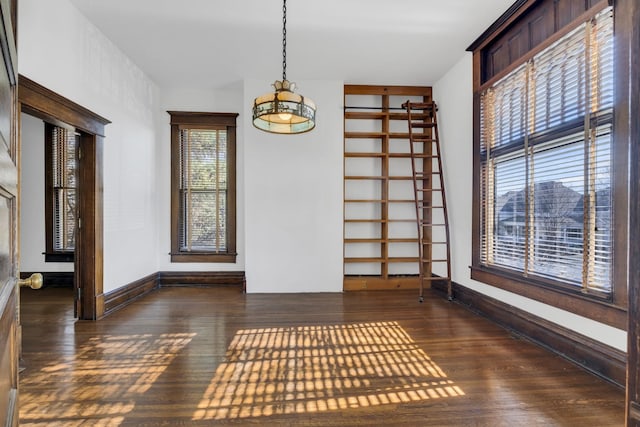 empty room with dark wood-type flooring and a notable chandelier