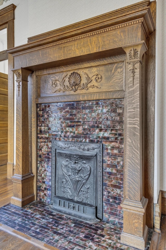 room details featuring wooden walls, a tile fireplace, and ornate columns