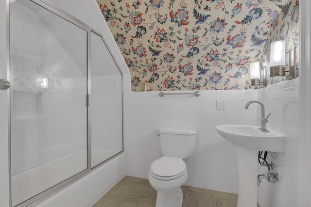 full bathroom with tile patterned floors, toilet, sink, combined bath / shower with glass door, and tile walls