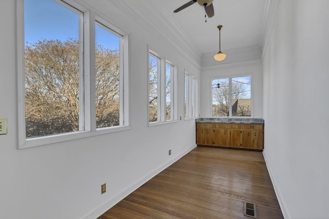 unfurnished sunroom with ceiling fan and plenty of natural light