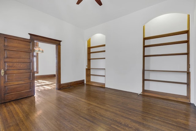 empty room featuring ceiling fan, dark hardwood / wood-style flooring, and built in features