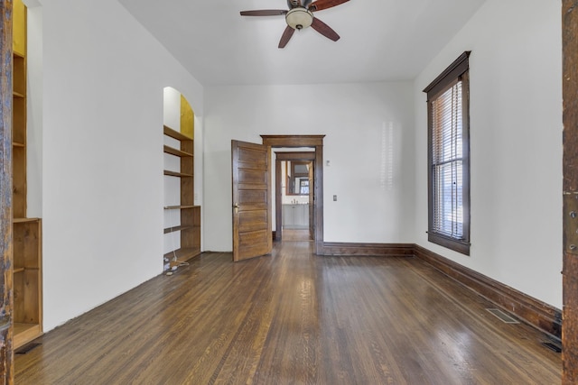 spare room featuring built in shelves, ceiling fan, and dark hardwood / wood-style floors