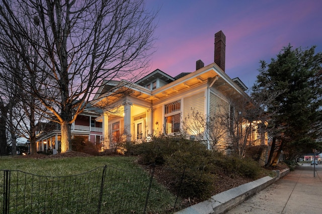 view of front of house featuring a yard, fence, and a chimney