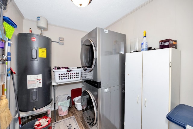 laundry room with ornamental molding, cabinets, hardwood / wood-style flooring, stacked washer / drying machine, and electric water heater