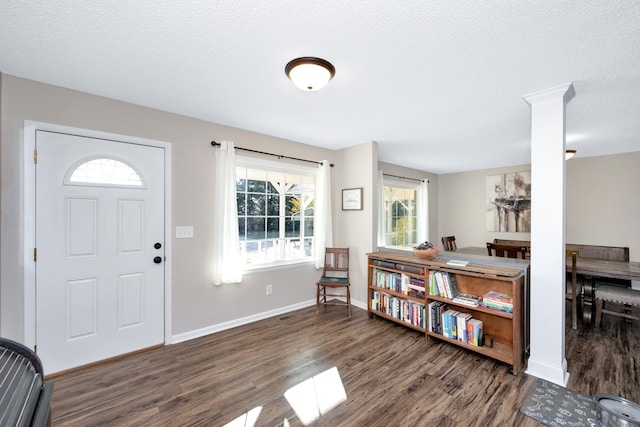 foyer featuring plenty of natural light, ornate columns, a textured ceiling, and dark hardwood / wood-style flooring