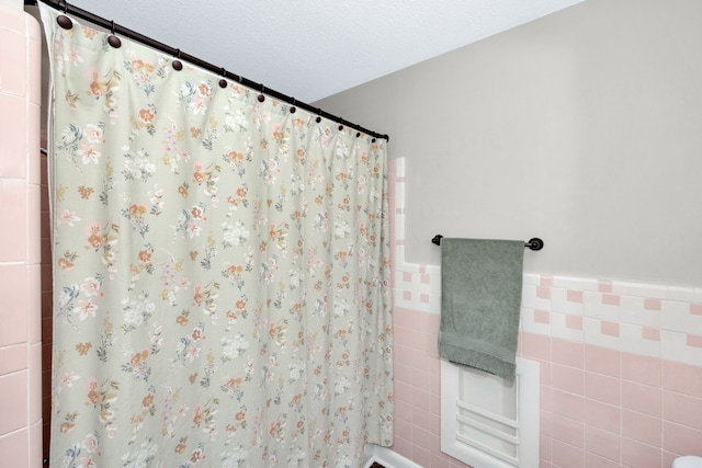 bathroom with a textured ceiling and tile walls