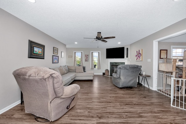 living room with dark wood-type flooring, ceiling fan, a healthy amount of sunlight, and a textured ceiling