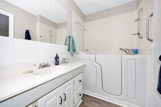 bathroom featuring a bathing tub, wood-type flooring, tasteful backsplash, and vanity