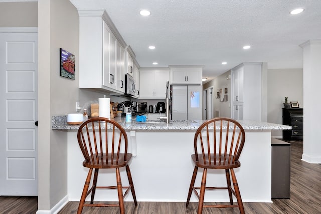 kitchen with white cabinetry, kitchen peninsula, dark wood-type flooring, and a textured ceiling