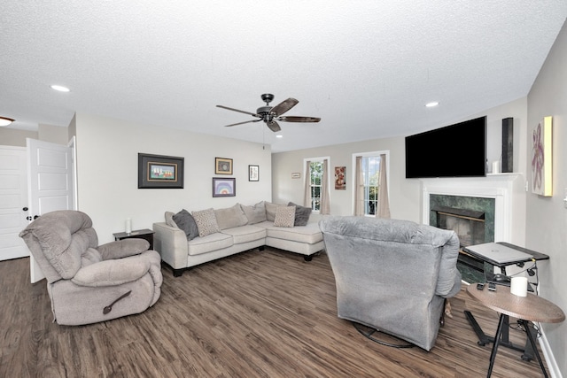 living room with dark hardwood / wood-style flooring, a textured ceiling, a high end fireplace, and ceiling fan