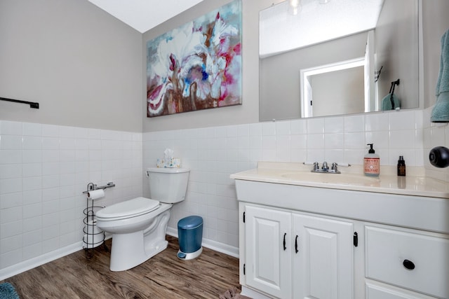 bathroom with toilet, vanity, tile walls, and hardwood / wood-style floors