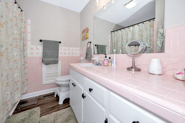 bathroom with hardwood / wood-style floors, vanity, toilet, and tile walls