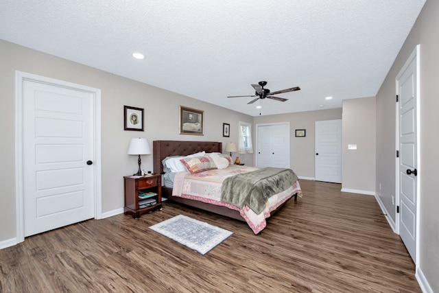 bedroom featuring dark wood-type flooring, a textured ceiling, and ceiling fan