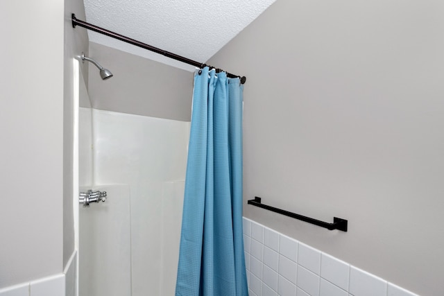 bathroom with walk in shower, tile walls, and a textured ceiling