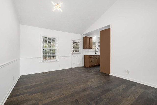 unfurnished living room with dark wood-type flooring, high vaulted ceiling, and sink