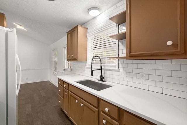 kitchen featuring sink, decorative backsplash, a textured ceiling, white refrigerator, and dark hardwood / wood-style flooring