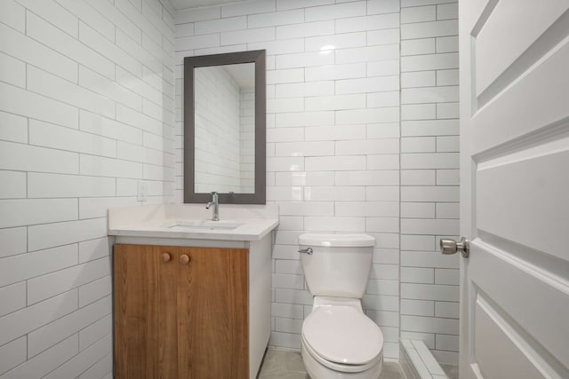 bathroom featuring tile walls, vanity, toilet, and tile patterned floors