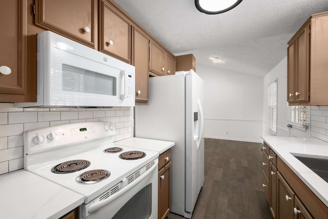 kitchen featuring tasteful backsplash, dark wood-type flooring, a textured ceiling, and white appliances