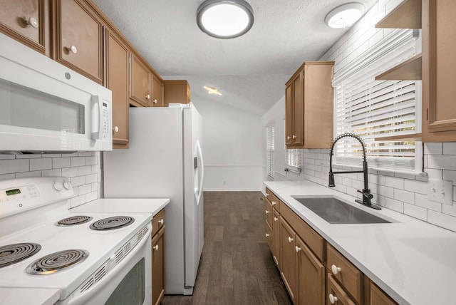 kitchen featuring dark wood-type flooring, white appliances, sink, and a textured ceiling