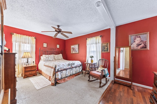 bedroom featuring a textured ceiling, dark hardwood / wood-style flooring, multiple windows, and ceiling fan