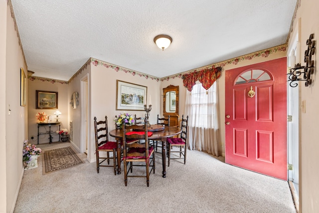 carpeted dining space featuring a textured ceiling