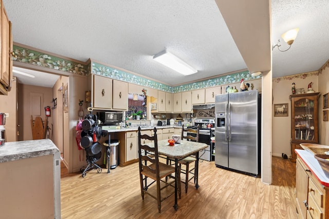 kitchen with light wood-type flooring, stainless steel appliances, and a textured ceiling