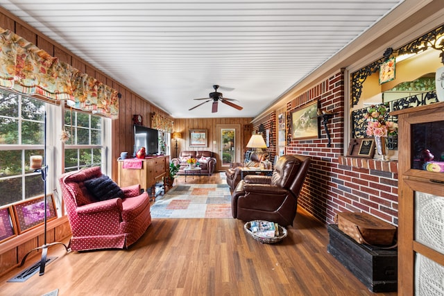 living room featuring wood walls, ceiling fan, brick wall, and wood-type flooring