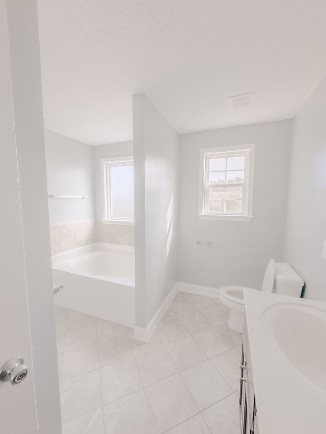 bathroom featuring vanity, tile patterned flooring, a washtub, and toilet