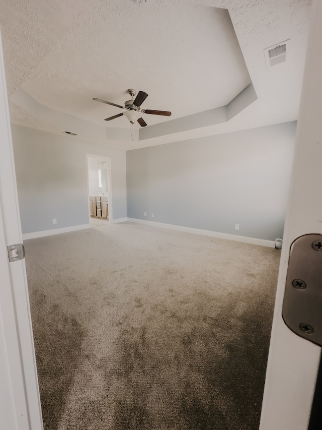 spare room with ceiling fan, a textured ceiling, carpet floors, and a tray ceiling