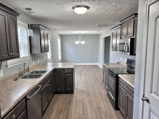 kitchen featuring stainless steel appliances, dark wood-type flooring, an inviting chandelier, sink, and decorative light fixtures