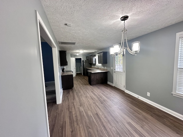 kitchen with sink, dark hardwood / wood-style floors, a textured ceiling, a center island, and stainless steel fridge