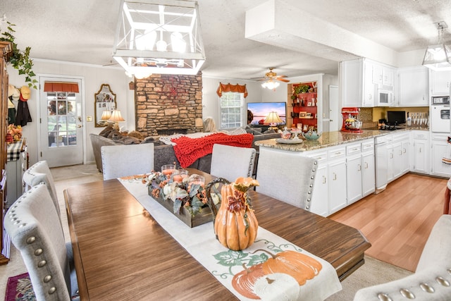 dining room with plenty of natural light, a fireplace, light wood-type flooring, and a textured ceiling