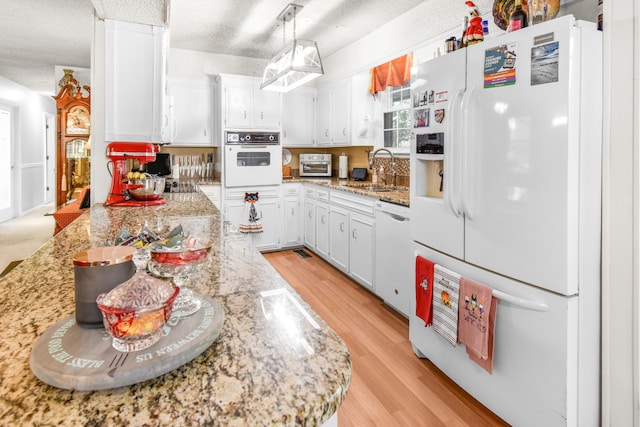 kitchen with a textured ceiling, white appliances, light hardwood / wood-style flooring, white cabinetry, and hanging light fixtures