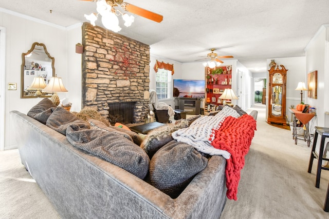 carpeted living room featuring a fireplace, a textured ceiling, ceiling fan, and crown molding