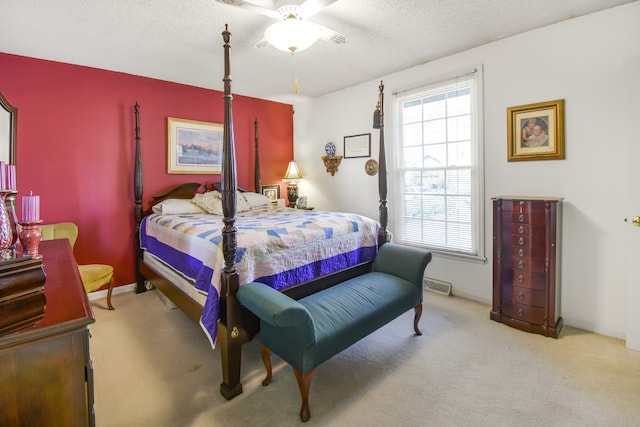 bedroom with light carpet, a textured ceiling, and ceiling fan