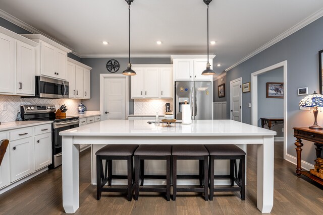 kitchen with stainless steel appliances, a center island with sink, and decorative light fixtures