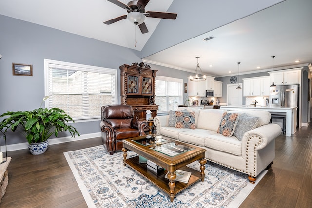 living room featuring vaulted ceiling, dark hardwood / wood-style floors, ceiling fan with notable chandelier, and crown molding