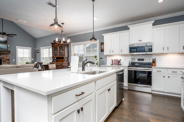 kitchen with stainless steel appliances, a center island with sink, sink, decorative light fixtures, and dark hardwood / wood-style flooring