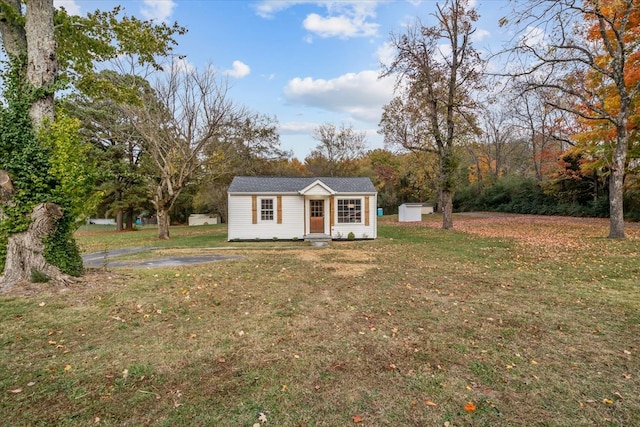 view of front of home featuring a front yard and a storage shed