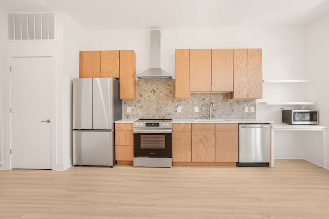 kitchen with light wood-type flooring, wall chimney range hood, sink, and stainless steel appliances