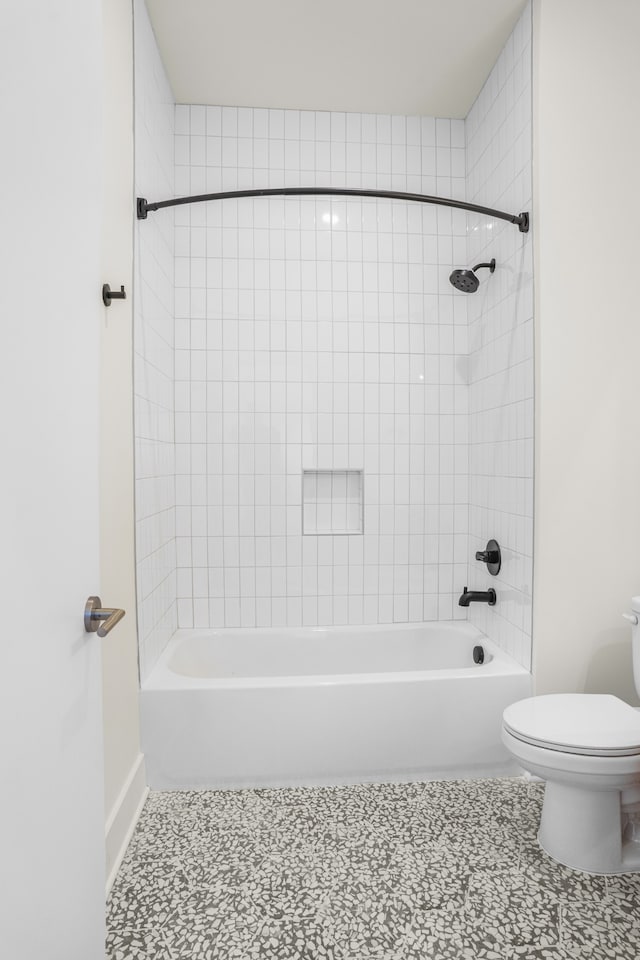 bathroom featuring tile patterned floors, toilet, and tiled shower / bath