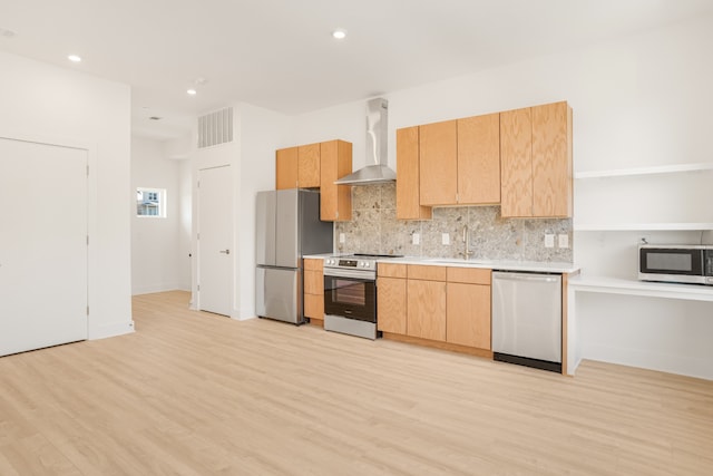 kitchen featuring stainless steel appliances, light wood-type flooring, light brown cabinetry, sink, and wall chimney exhaust hood