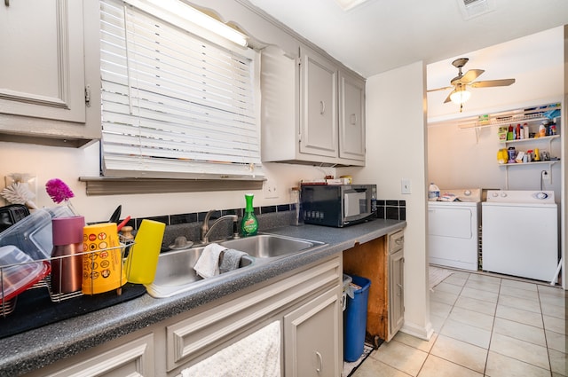 clothes washing area with washing machine and clothes dryer, ceiling fan, light tile patterned floors, and sink